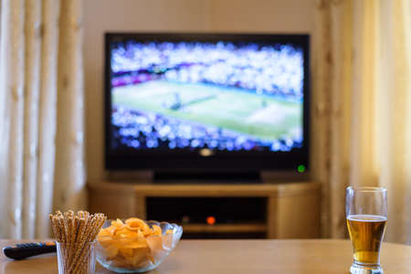 Television, TV watching (tennis match) with snacks and alcohol lying on table - stock photoの写真素材