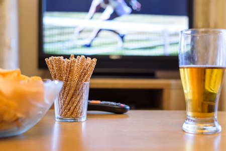 Television, TV watching (tennis match) with snacks and alcohol lying on table - stock photoの写真素材