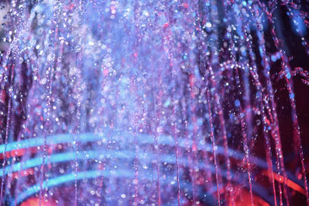 Multicolored spray fountain at nightの写真素材