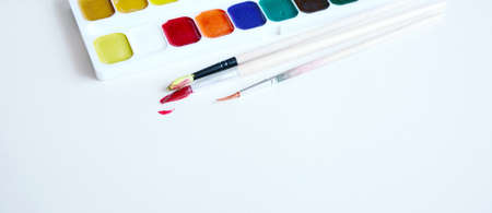 Paint brushes and a set of paints on a white paperの写真素材