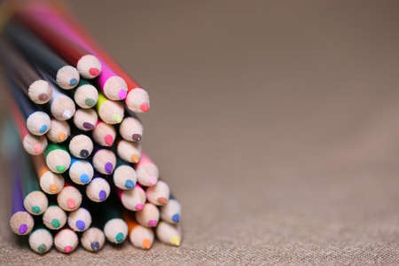 Multicolored pencils on the table. A stack of colored pencils tied together. A scattering of writing supplies and stationery.の写真素材