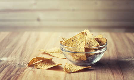 Corn chips in the jar. Traditional snack for beer Mexican nachos. Nachos with spices and pepper on wooden table.の写真素材