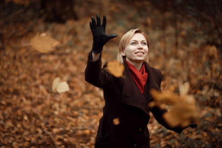 girl walking in autumn Park. Tree with yellow leaves flying up.