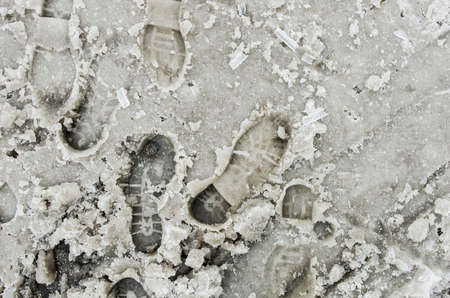 Dirty footprints in the snow winter. Track from boots on the tra