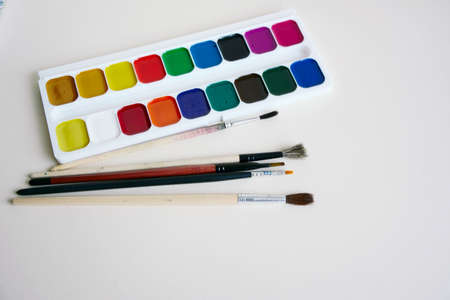 Paint brushes and a set of paints on a white paperの写真素材