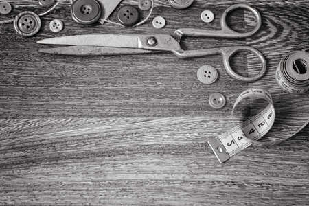Scissors and buttons on a wooden background black whiteの写真素材