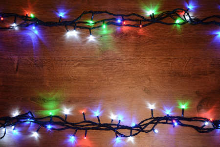 New-year electric garland on a wooden background. Bright bulbs o
