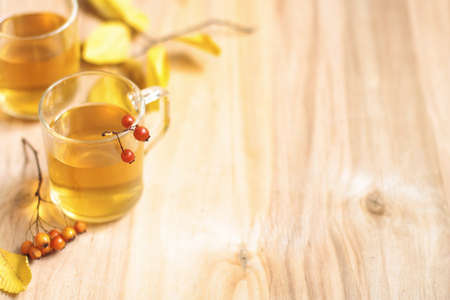 Tea in glass on a wooden table with leaves and berries