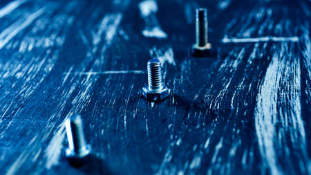 Nuts for repairs lying on a wooden table. Iron nuts and screws f