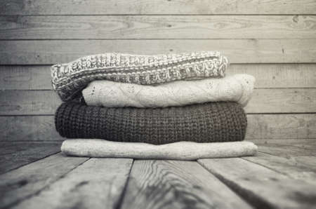 Knitted sweaters and leaves on a wooden background