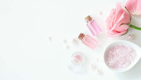 Aromatherapy. Small glass bottles with cosmetic oils. Bath salt. Fresh rose. Objects for spa procedures on white background oil, flower.の写真素材