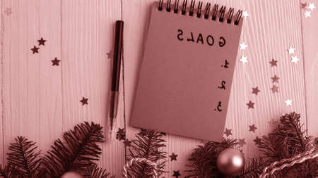 A Notepad on a wooden table near the Christmas tree. Notebook to
