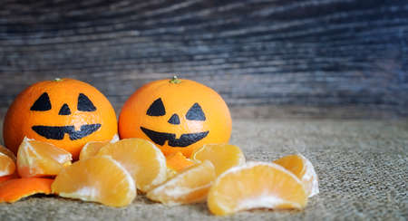 Painted scary faces on a holiday of halloween on orange fruitsの写真素材