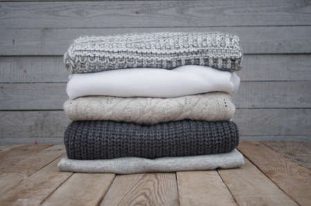 Knitted sweaters and fallen yellow leaves on a wooden backgroundの写真素材