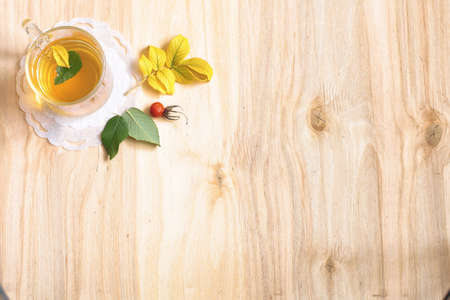 Tea in glass on a wooden table with leaves and berriesの写真素材