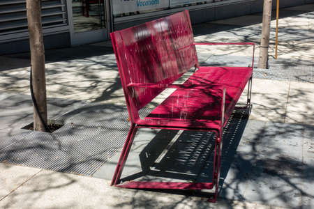 A view of a red bench on a sidewalk in the cityの写真素材