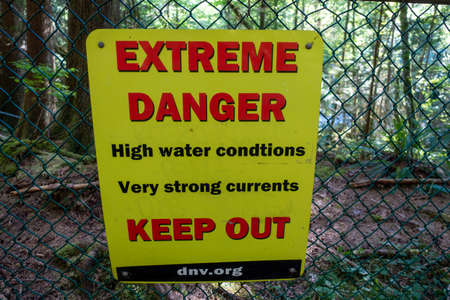 Danger sign on a chain link fence in the forest. High quality photo