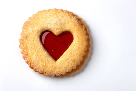 a biscuit with jam in the shape of a heart on a white backgroundの写真素材