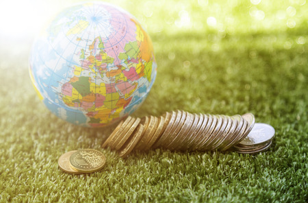 Small world and coins money on the grass surfaceの写真素材