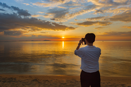Business man use smartphone take a picture of sunsetの写真素材