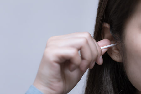 Young woman is using cotton bud with her ears, beauty conceptの写真素材