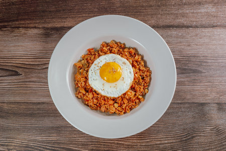 Korean food kimchi fried rice dish with fried egg on white plateの写真素材