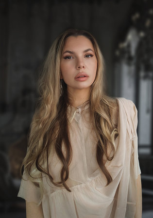 Portrait of a beautiful girl with long hair in a beige blouseの写真素材