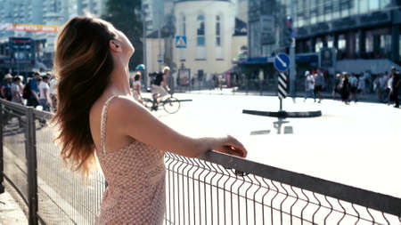 Young woman with long hair look at the street in the city. People pedestrians crossing crosswalk on the background.の写真素材
