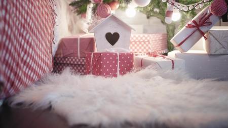 Young pretty woman in red high-heeled shoes puts Christmas present under a Christmas tree. Close up view legsの写真素材