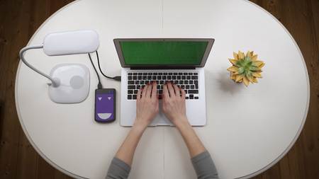 Woman freelancer connected an external hard drive to the laptop and works on it. Chroma key. Top view. Hands close upの写真素材