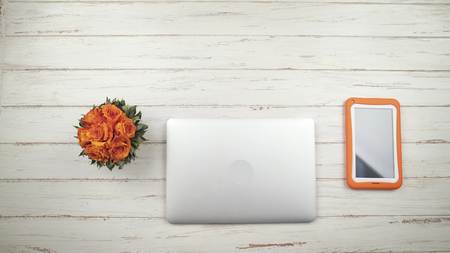 Hipster woman opens a laptop, standing on the white wooden table with flowers, typing text and closing a laptop. Top view. Hands close upの写真素材
