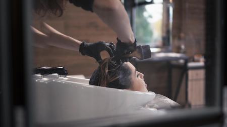 Hairdresser paints hair of woman in a wash
