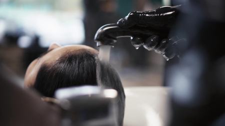 Hairdresser in gloves washes the brunette girls hair in a stylish beauty salon. barbershopの写真素材
