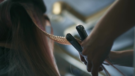 Hairdresser makes wavy hair with tongs.の写真素材