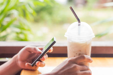 hand hold coffee and use smart phoneの写真素材