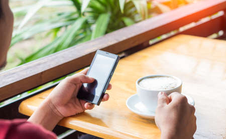 man drink coffee and use smart phone in coffee shop at eveningの写真素材
