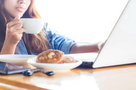 women drink coffee and use laptop computer outdoorの写真素材