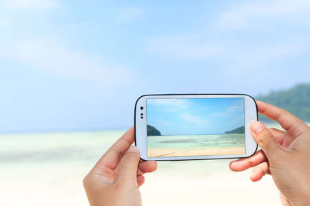 close up hand use smart phone take photography the beachの写真素材