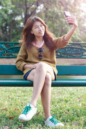 women use smartphone taking self picture selfie camera in bright dayの写真素材