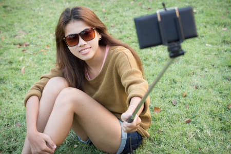 pretty girl smile take self picture selfie with smart phone mobile outdoorの写真素材