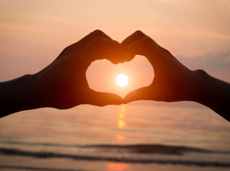 couple holding hands heart love at sunset on the beach, valentine dayの写真素材