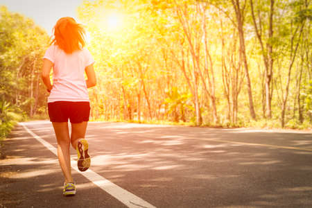 Young women running on rural road during sunsetの写真素材