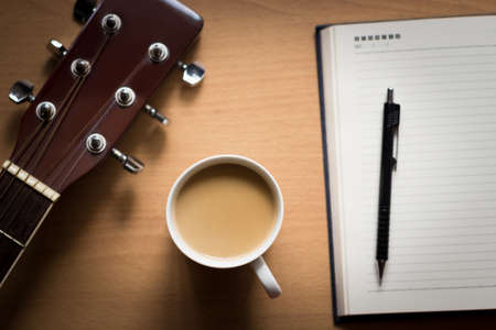 hot coffee with guitar and notepad on table break time for thinking ideaの写真素材
