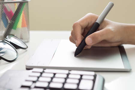closeup designer hand using graphic tablet on deskの写真素材