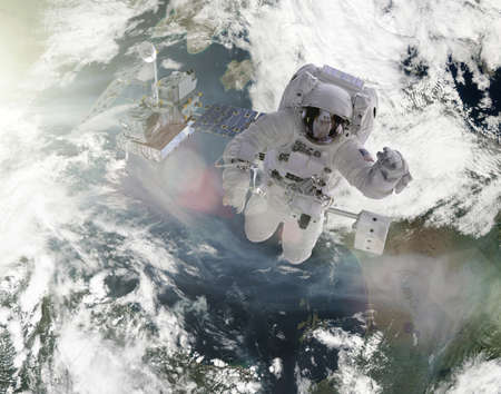astronauts perform work on satellite in space over the earth elements of this image furnished by...