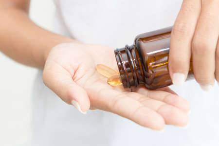 closeup hand holding fish oil vitamin for healthyの写真素材