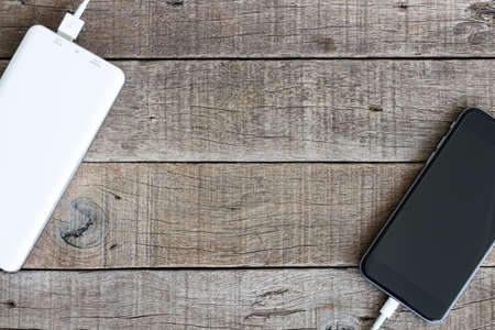phone charging with power bank on wood backgroundの写真素材