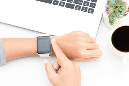 woman touching smart watch hand on work deskの写真素材