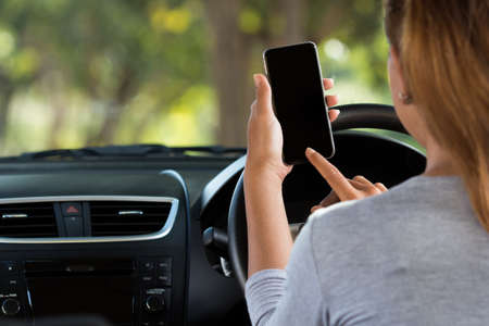 woman using phone in car on roadの写真素材