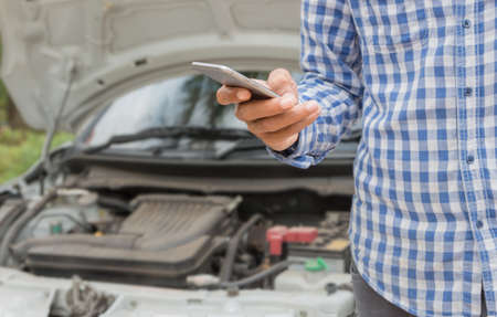 closeup man using phone call emergency car serviceの写真素材